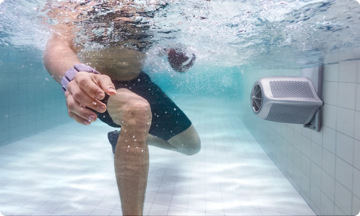 Mann, der Unterwasser-Aerobic-Bewegungen durchführt und stetig gegen die mäßige Strömung des iGarden Swim Jet trainiert