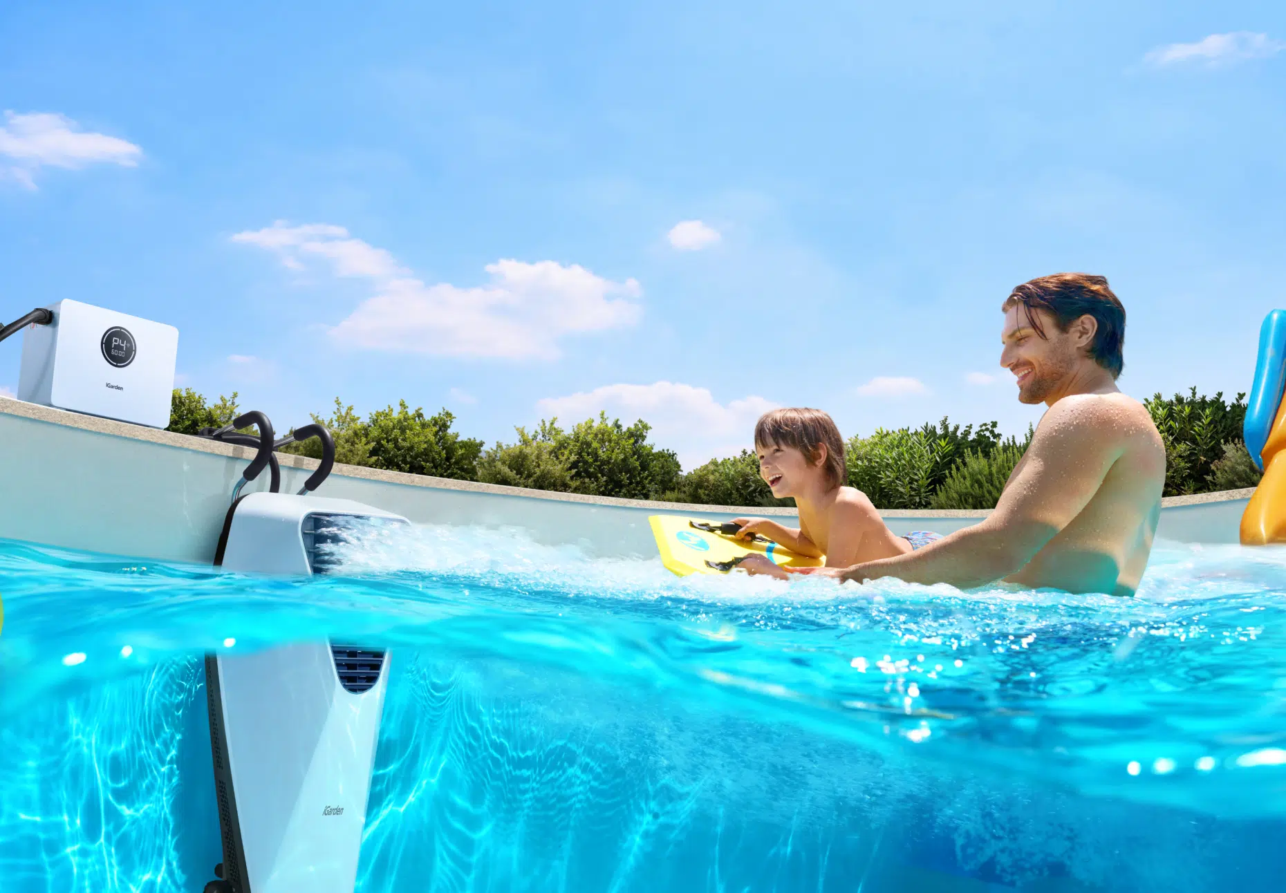 Um pai e seu filho desfrutam de diversão em família com o sistema de nado contra a correnteza portátil iGarden Swim Jet X em uma piscina enterrada.